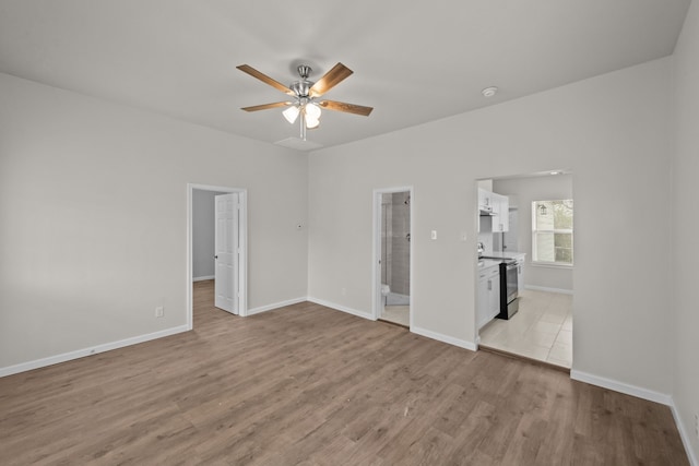 interior space featuring ceiling fan, light wood-type flooring, and baseboards