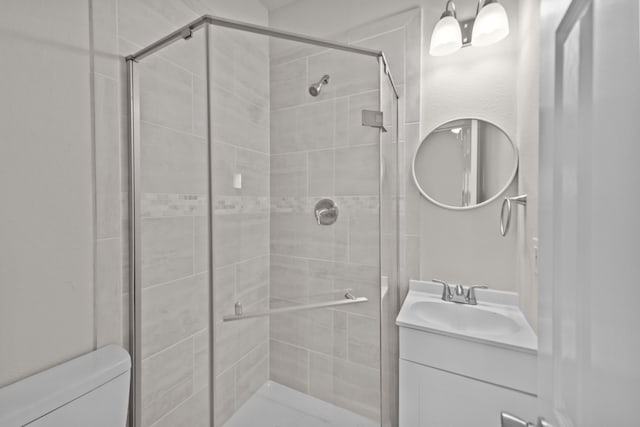 bathroom featuring vanity, a shower stall, and toilet