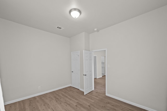 unfurnished bedroom with wood finished floors, visible vents, and baseboards