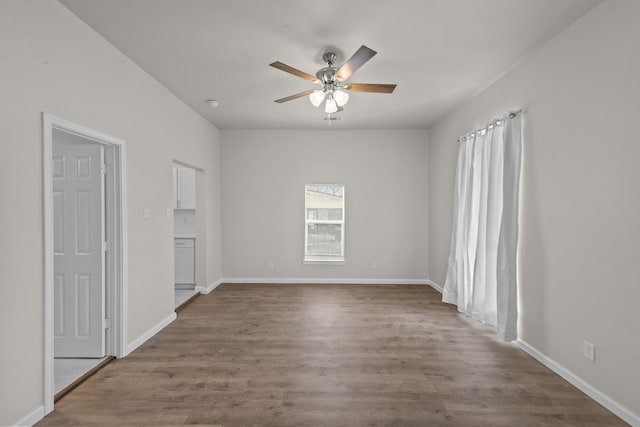 spare room featuring ceiling fan, baseboards, and wood finished floors