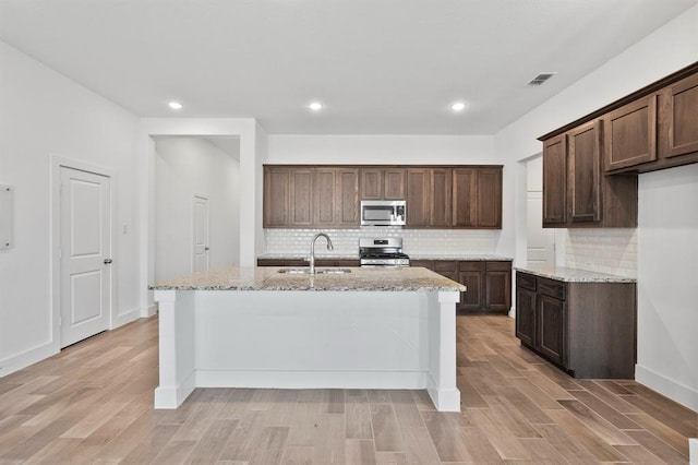 kitchen featuring light wood finished floors, appliances with stainless steel finishes, a sink, and visible vents