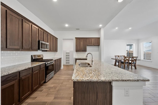 kitchen with visible vents, decorative backsplash, appliances with stainless steel finishes, a sink, and an island with sink