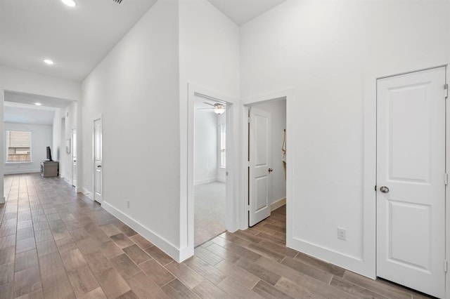 hall featuring wood tiled floor, baseboards, and recessed lighting