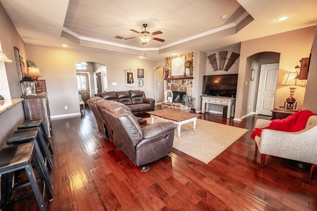 living room featuring visible vents, a tray ceiling, arched walkways, and dark wood-type flooring