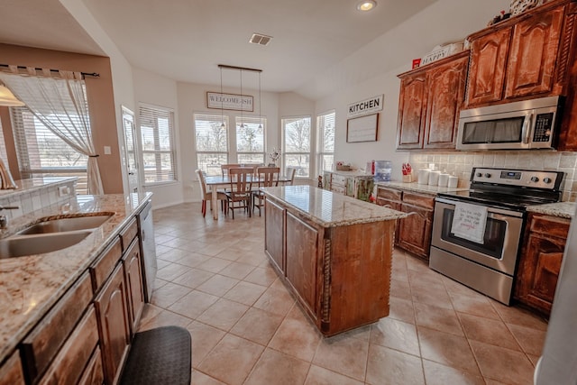 kitchen featuring light tile patterned floors, tasteful backsplash, visible vents, stainless steel appliances, and a sink