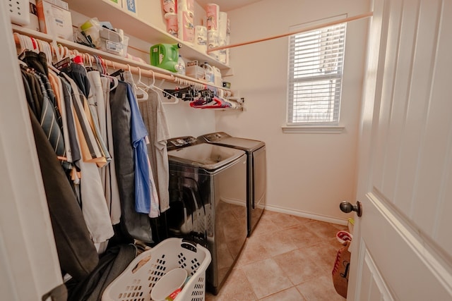 washroom with washing machine and dryer, laundry area, baseboards, and light tile patterned floors