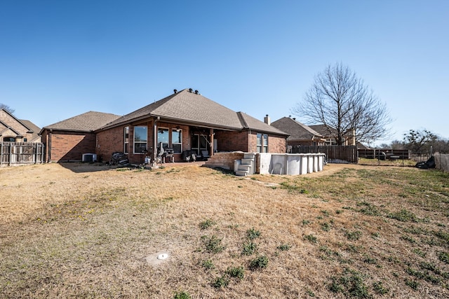 rear view of property featuring a fenced in pool, brick siding, and a fenced backyard