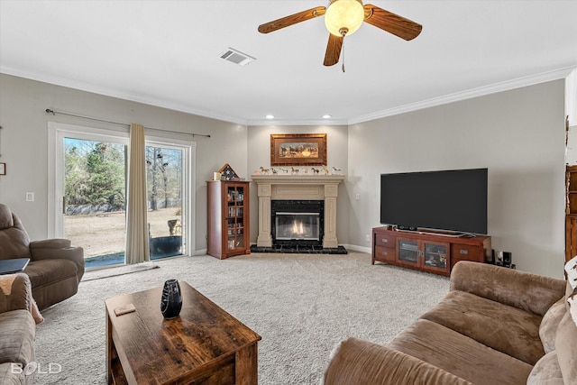 living area featuring carpet, a glass covered fireplace, visible vents, and crown molding