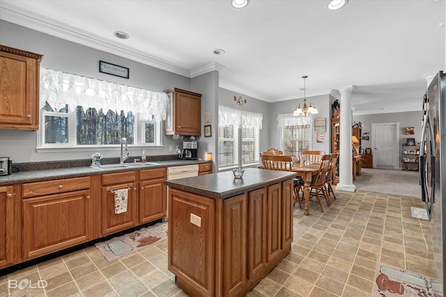 kitchen featuring brown cabinetry, dark countertops, a sink, and ornate columns