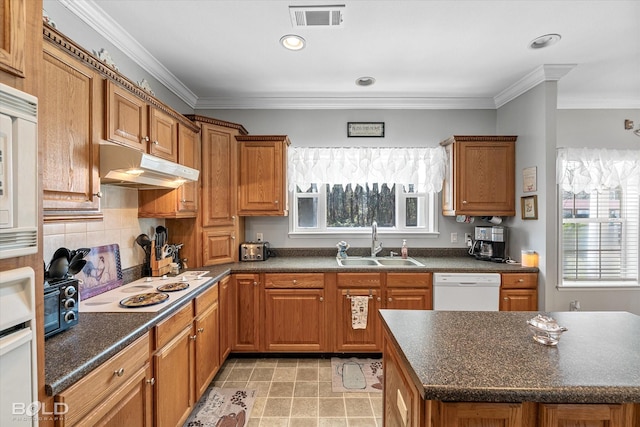 kitchen featuring under cabinet range hood, white appliances, a sink, visible vents, and ornamental molding