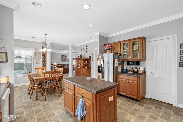 kitchen featuring brown cabinetry, dark countertops, stainless steel fridge, and crown molding