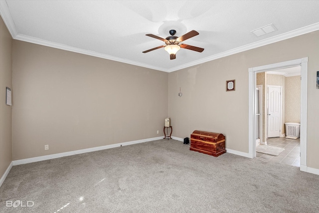 carpeted spare room featuring ornamental molding, a ceiling fan, and baseboards