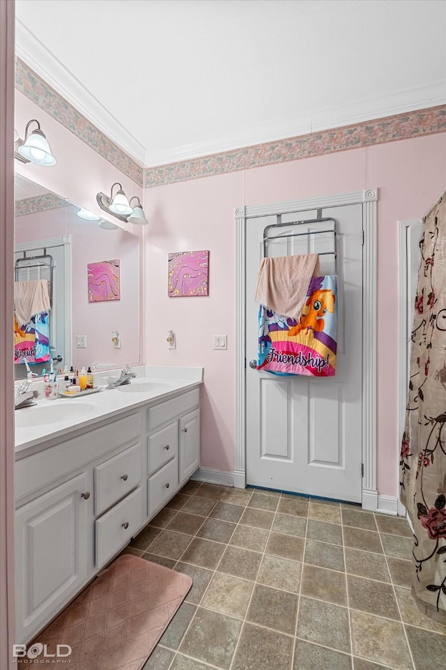 bathroom with double vanity, crown molding, baseboards, and a sink