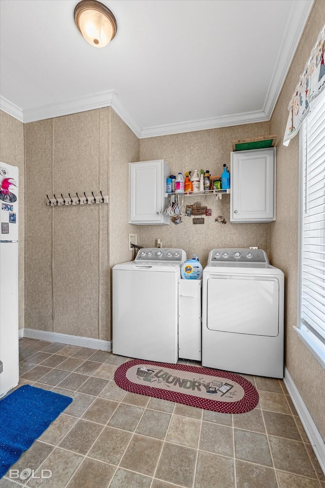 washroom featuring ornamental molding, washing machine and dryer, a wealth of natural light, and cabinet space