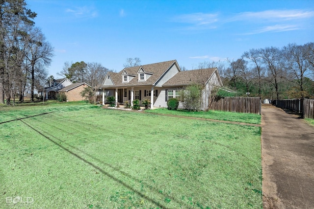 cape cod home with a front yard and fence