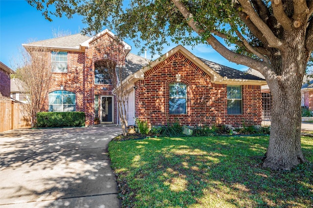 traditional-style home featuring driveway, a shingled roof, fence, a front lawn, and brick siding