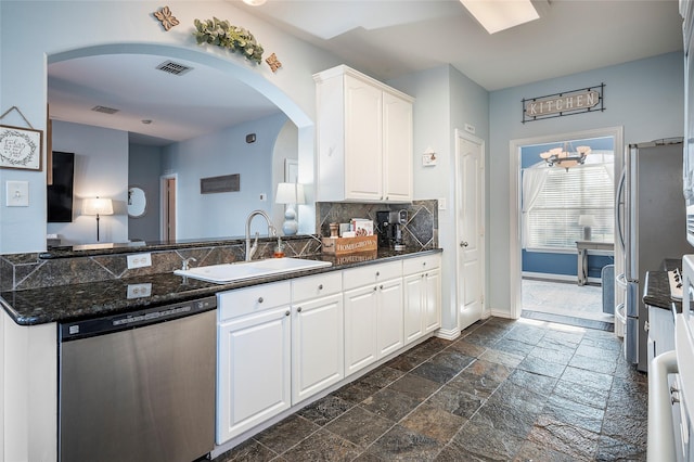 kitchen with stainless steel appliances, a sink, visible vents, white cabinets, and stone tile flooring