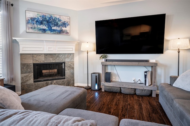 living room with a tile fireplace, baseboards, and wood finished floors