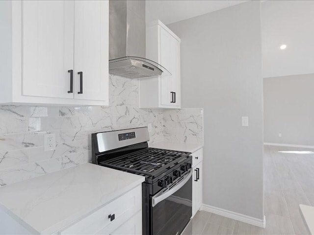kitchen featuring white cabinetry, baseboards, wall chimney range hood, tasteful backsplash, and stainless steel range with gas stovetop