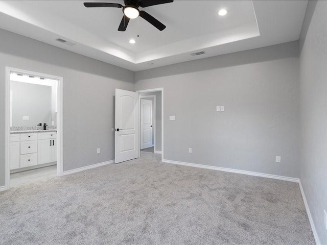 unfurnished bedroom featuring visible vents, baseboards, light colored carpet, a tray ceiling, and recessed lighting