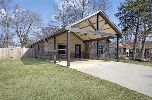 back of house with brick siding, a yard, fence, a carport, and driveway