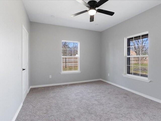 empty room with ceiling fan, plenty of natural light, carpet flooring, and baseboards