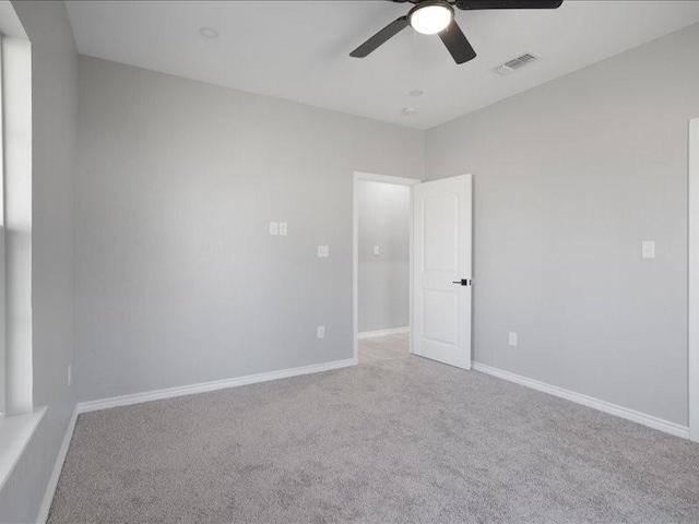 unfurnished room with carpet floors, baseboards, visible vents, and ceiling fan