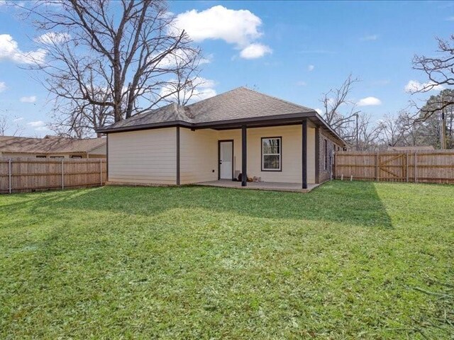 back of house featuring a fenced backyard, a lawn, brick siding, and a patio