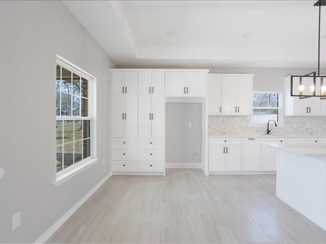 kitchen featuring light countertops, decorative light fixtures, white cabinetry, and baseboards