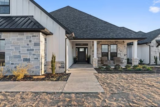 property entrance featuring a porch, board and batten siding, a standing seam roof, metal roof, and stone siding