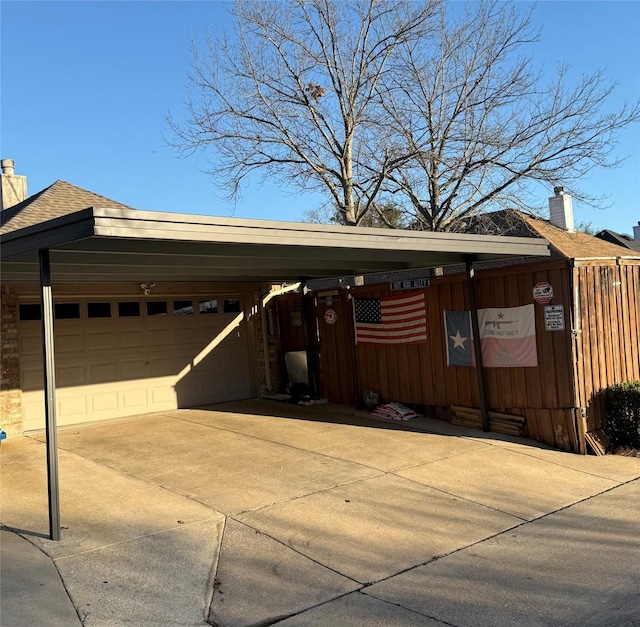 view of front facade with a chimney, a shingled roof, an attached garage, a carport, and driveway