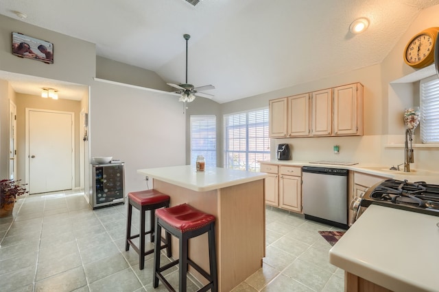 kitchen featuring lofted ceiling, light countertops, light brown cabinetry, a kitchen island, and dishwasher