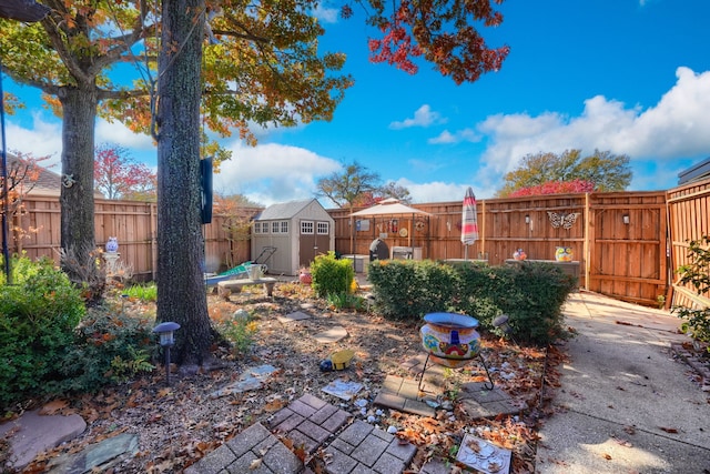 view of yard featuring a fenced backyard, a storage unit, and an outbuilding