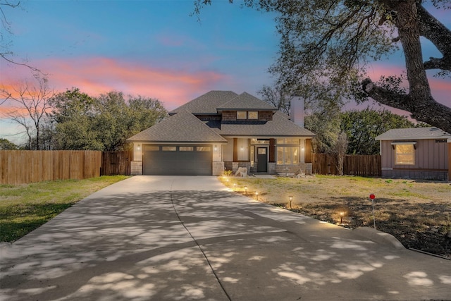 view of front facade featuring stone siding, fence, driveway, and an attached garage