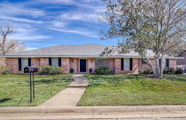 ranch-style house featuring brick siding, roof with shingles, and a front yard