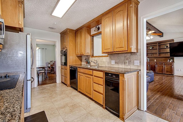 kitchen featuring visible vents, decorative backsplash, a textured ceiling, black appliances, and a sink