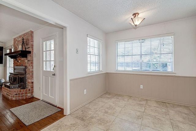 interior space featuring a textured ceiling, wainscoting, and light tile patterned flooring