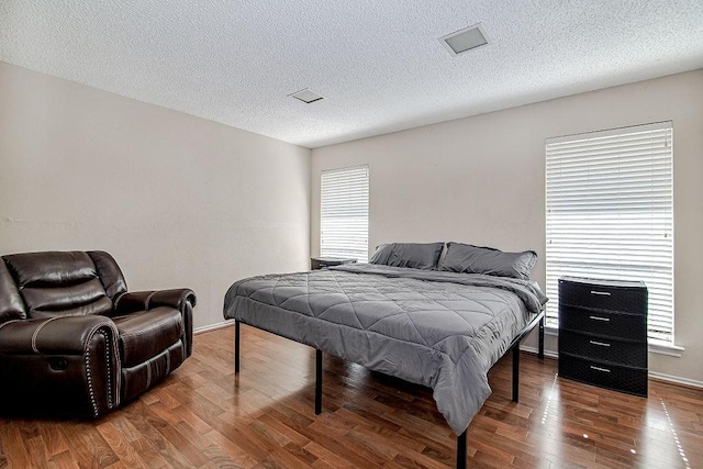 bedroom featuring a textured ceiling, baseboards, and wood finished floors