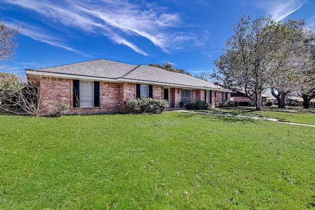 ranch-style house featuring a shingled roof, a front yard, and brick siding