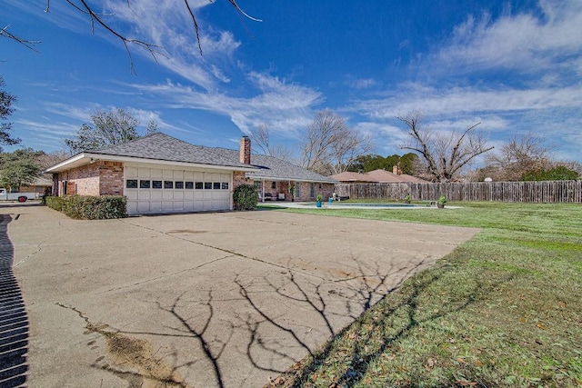 view of front of property with concrete driveway, an attached garage, fence, a front lawn, and brick siding