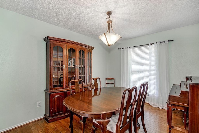 dining space with hardwood / wood-style flooring, baseboards, and a textured ceiling