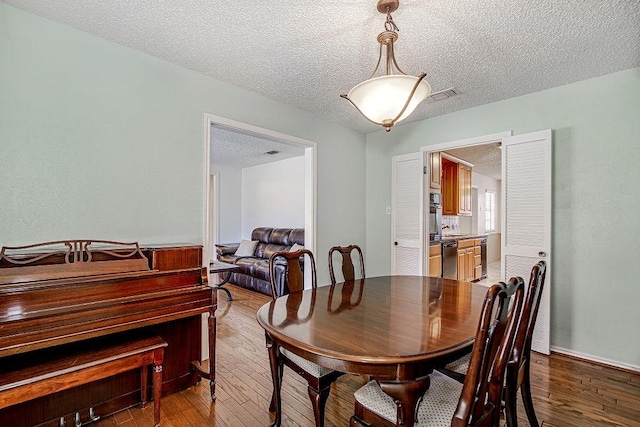 dining space featuring visible vents, a textured ceiling, and hardwood / wood-style floors