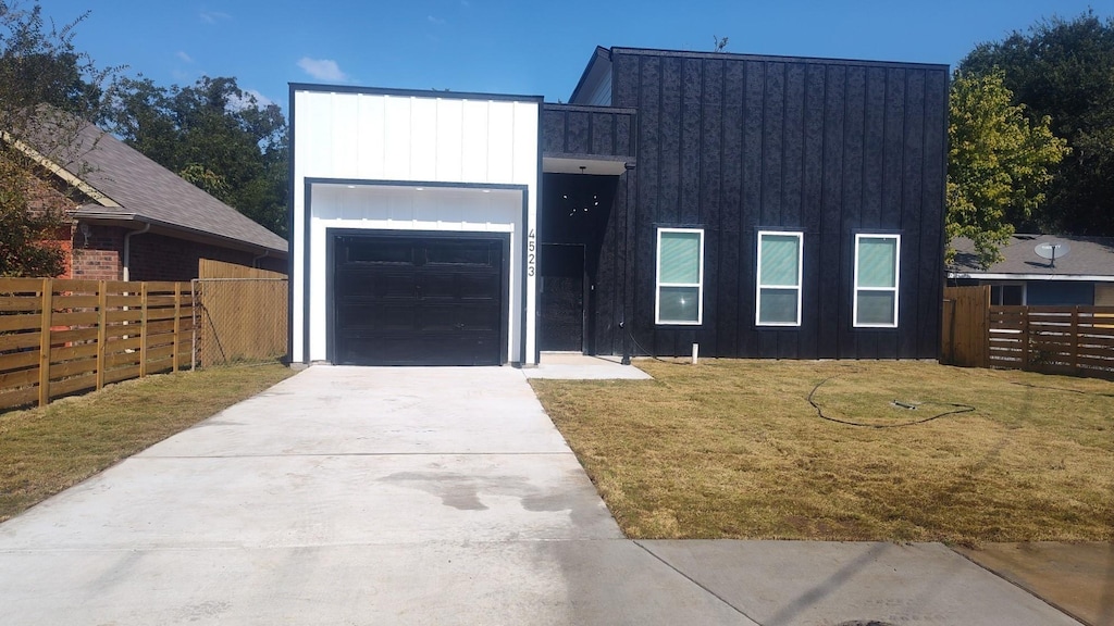 view of front facade with driveway, a garage, fence, a front lawn, and board and batten siding