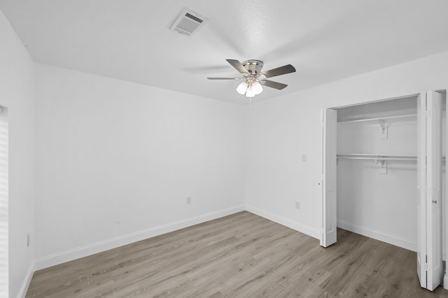 unfurnished bedroom featuring baseboards, visible vents, a ceiling fan, wood finished floors, and a closet