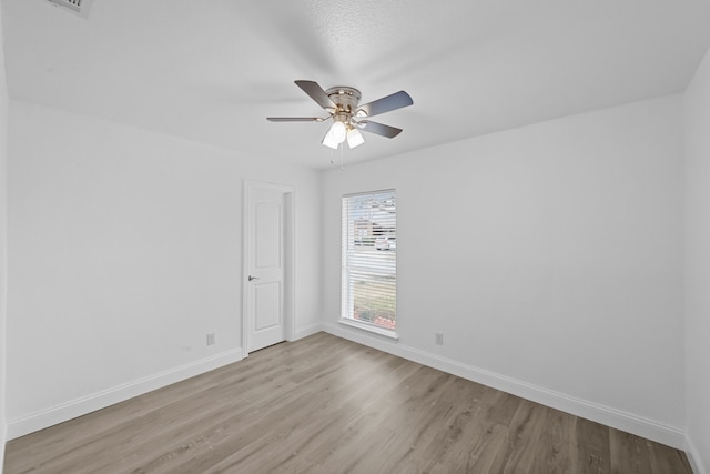 spare room with light wood finished floors, ceiling fan, and baseboards