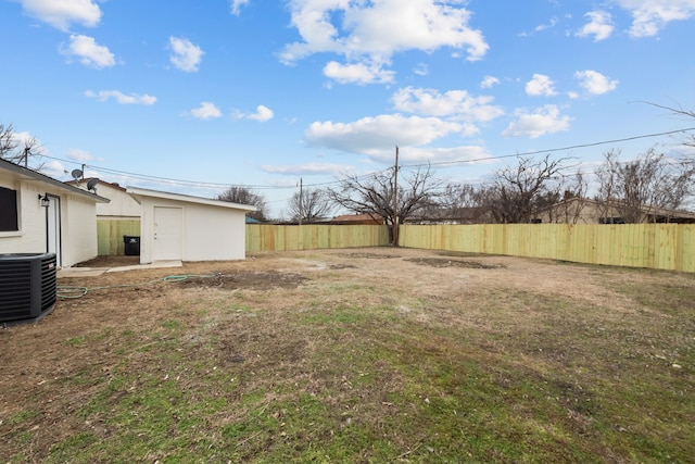 view of yard with a fenced backyard, a storage unit, central AC, and an outbuilding