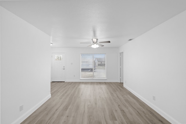 unfurnished living room with visible vents, a ceiling fan, light wood-style flooring, and baseboards