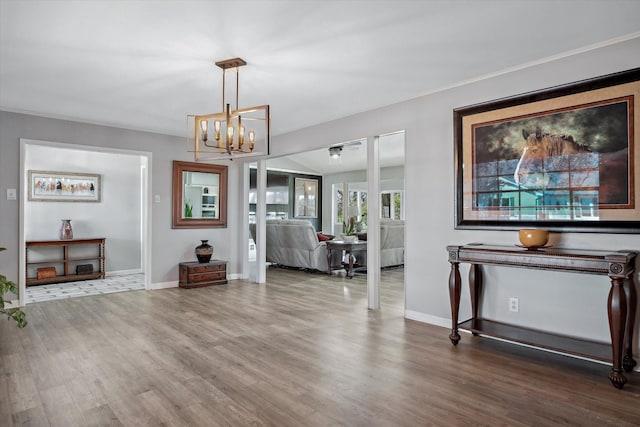 foyer entrance with an inviting chandelier, crown molding, baseboards, and wood finished floors