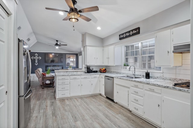 kitchen featuring stainless steel appliances, lofted ceiling, decorative backsplash, a sink, and light wood-type flooring