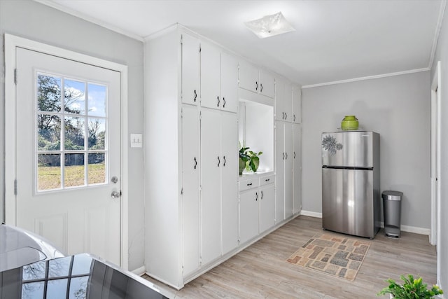 kitchen with baseboards, freestanding refrigerator, crown molding, light wood-type flooring, and white cabinetry